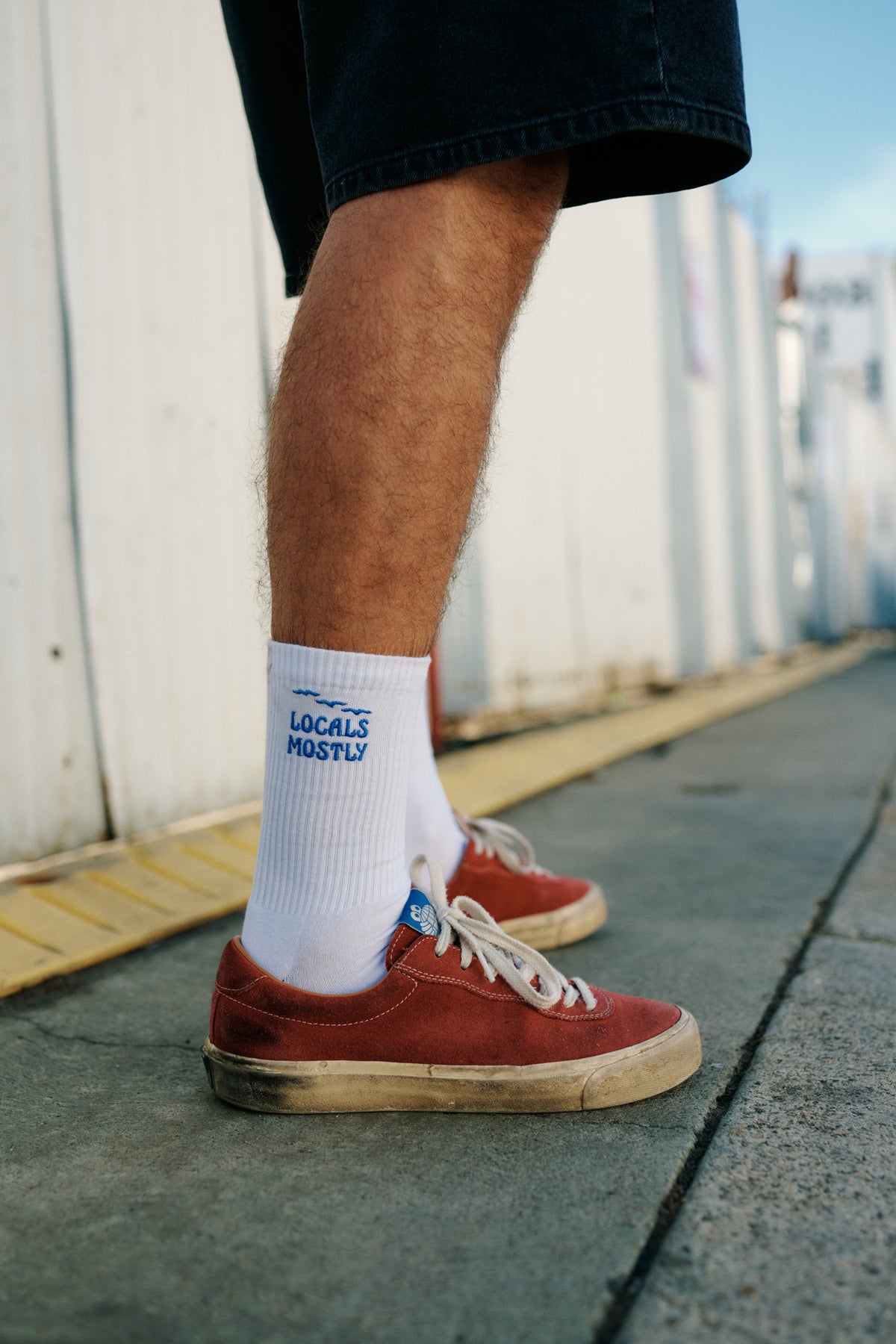 man wearing white socks with the saying "Locals Mostly" in blue