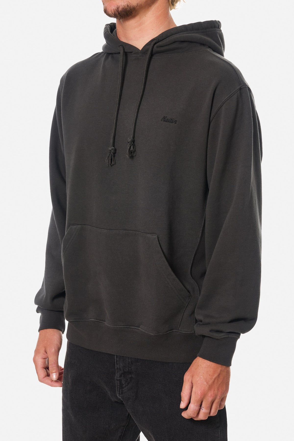 Person wearing a black wash hoodie sweatshirt with an embroidered Katin logo on a white background