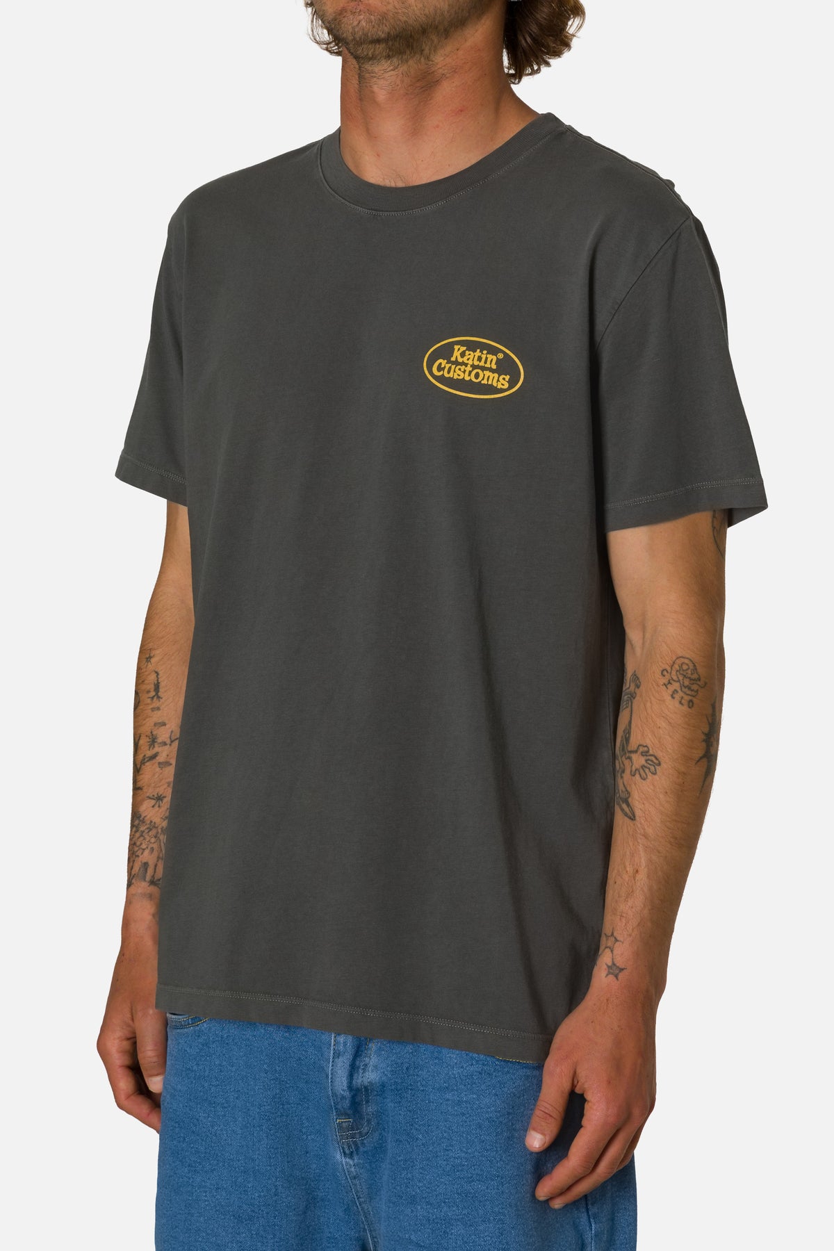 Person wearing a dark gray t-shirt with a yellow logo on a white background