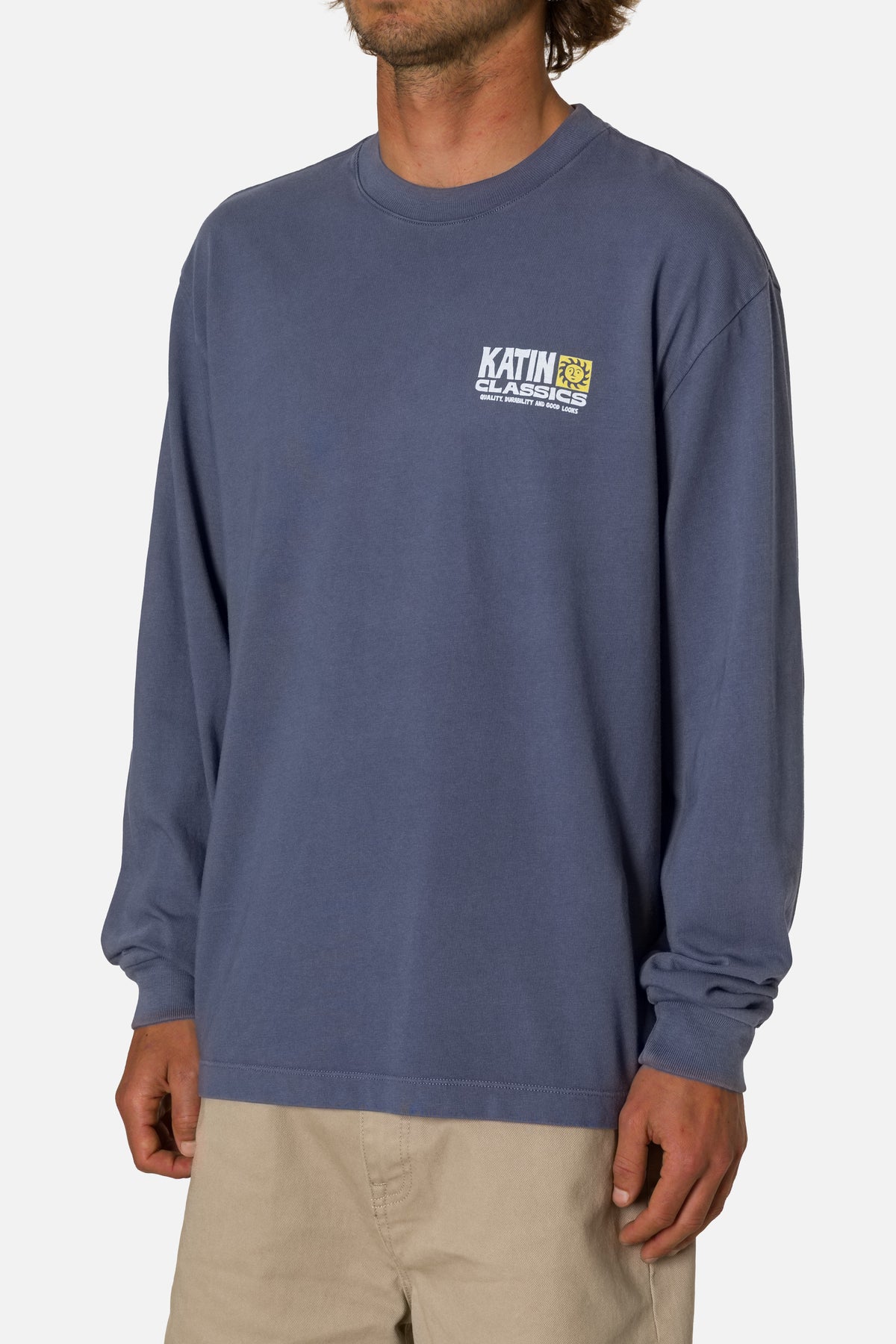 Man wearing a blue long-sleeve shirt with a logo on a white background
