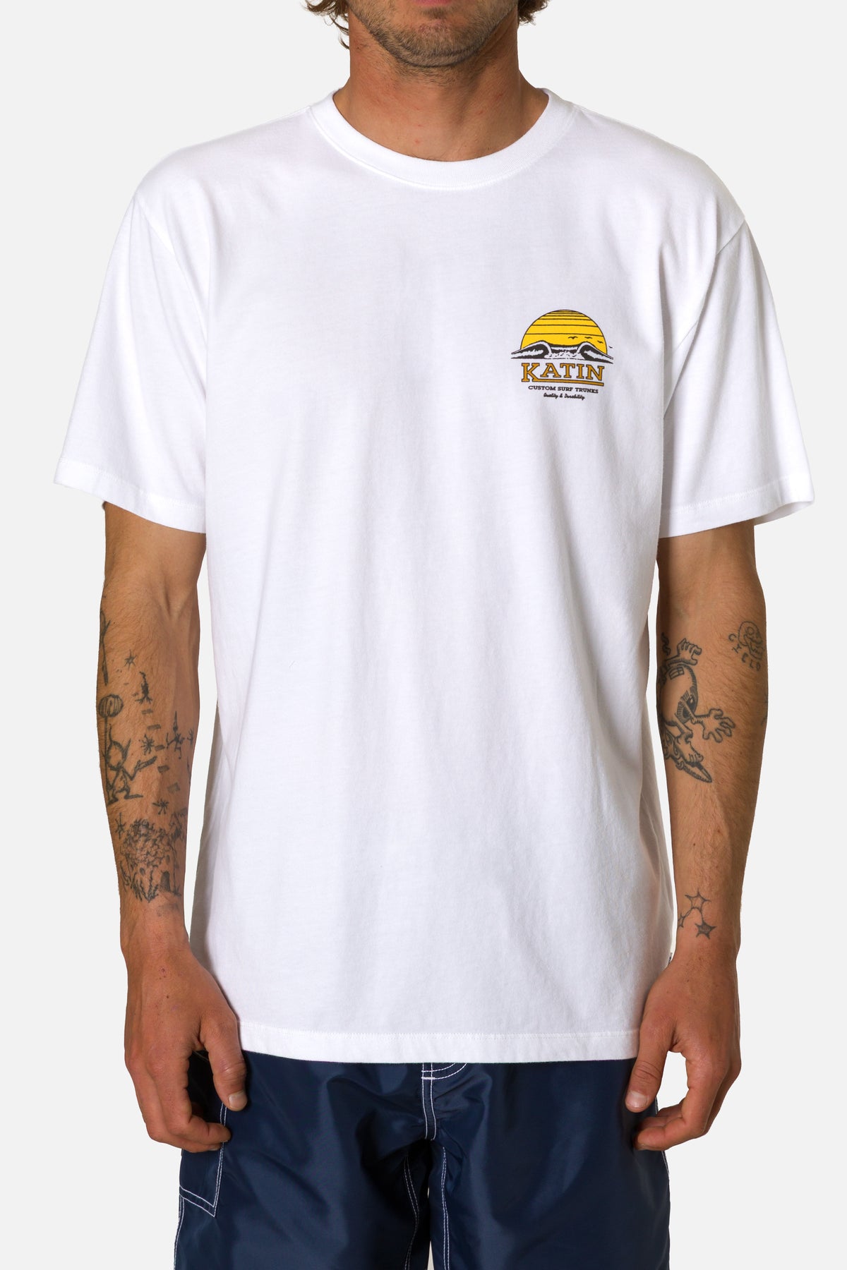 Person wearing a white t-shirt with a logo and text on a plain background