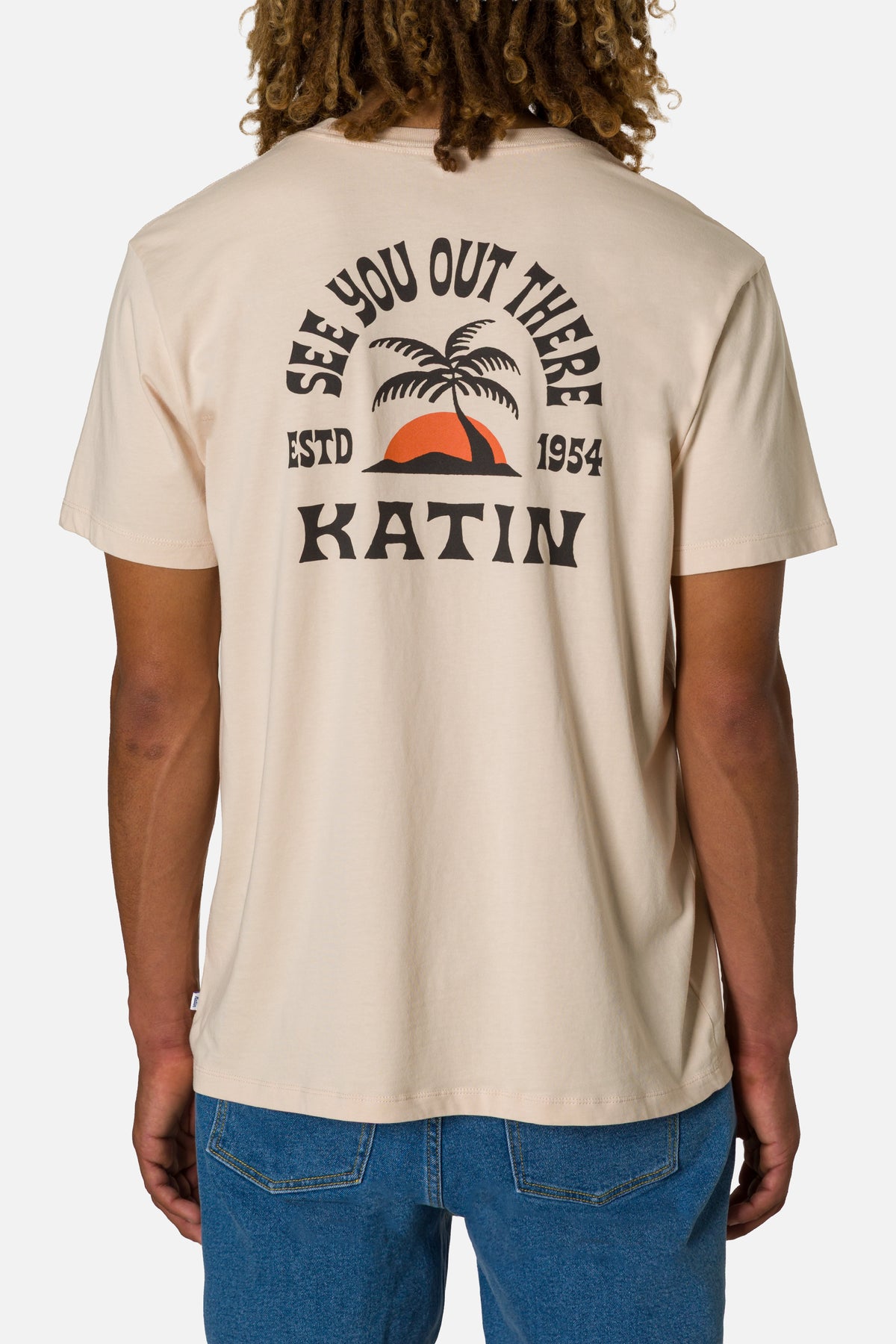 Person wearing a beige t-shirt with 'Katin' branding and palm tree design.