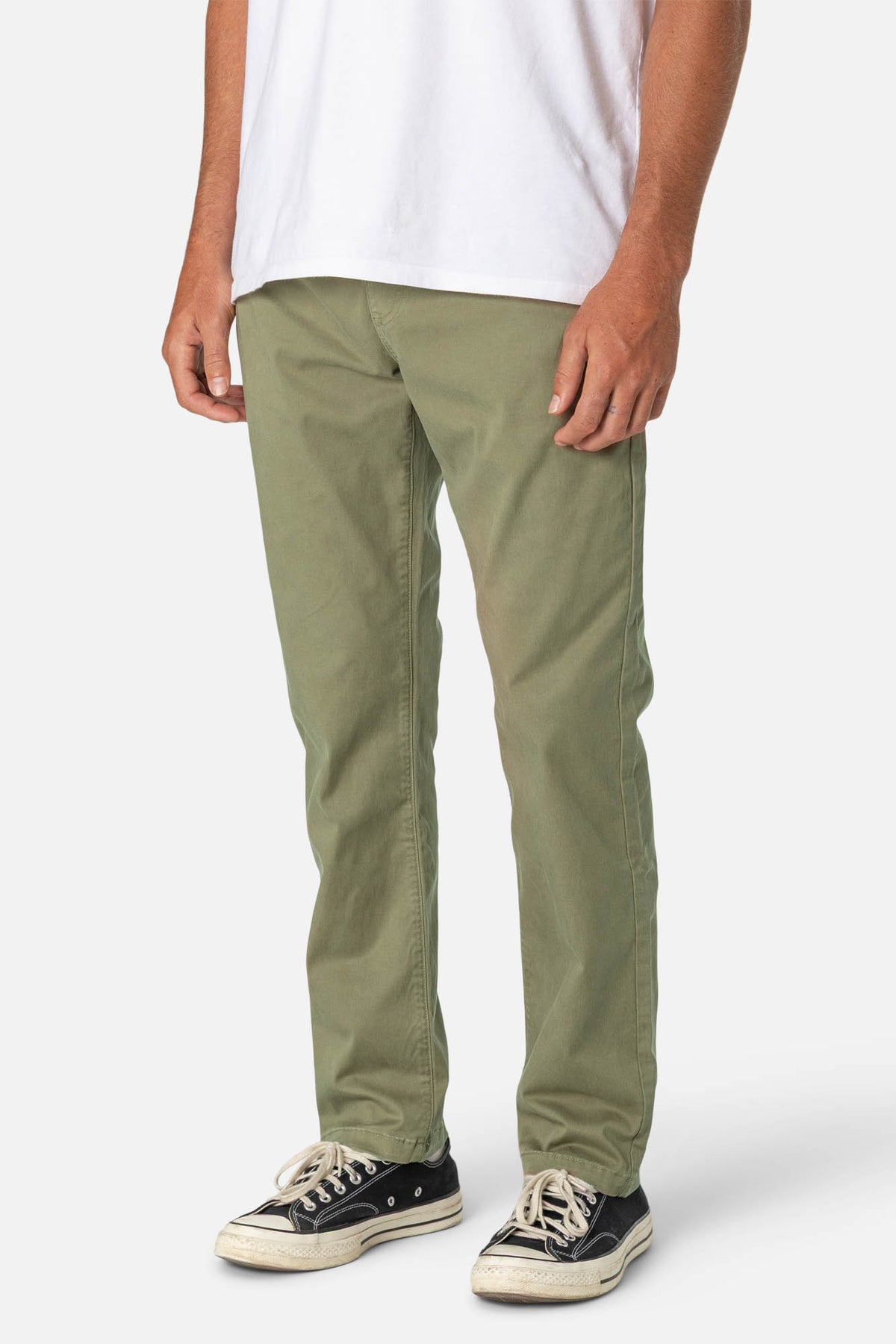 Person wearing olive green pants and black sneakers on a white background