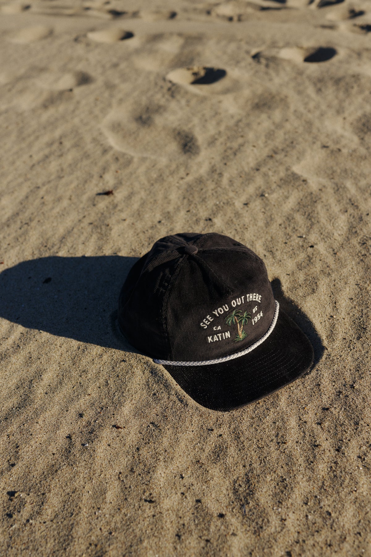 Black cap with text on a sandy surface