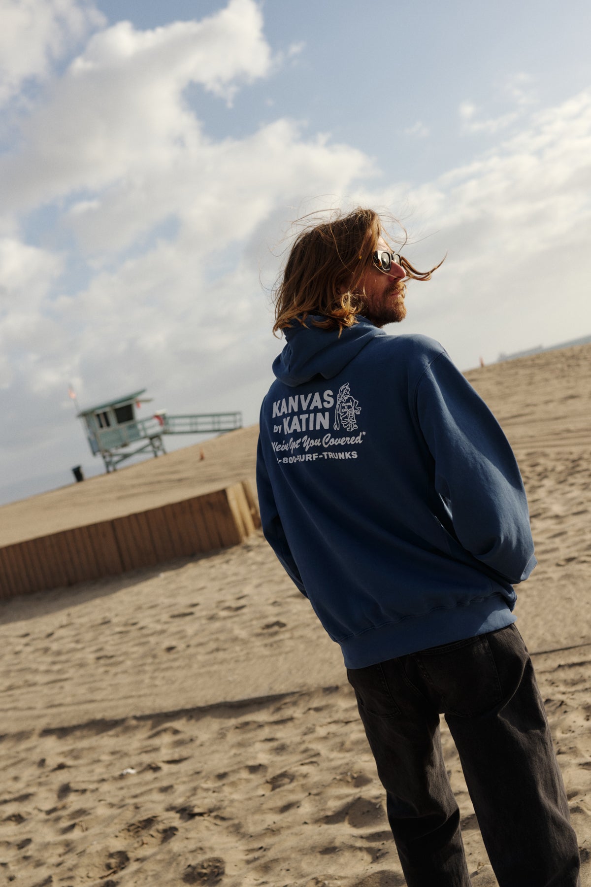 Person wearing a blue hoodie with text on the beach