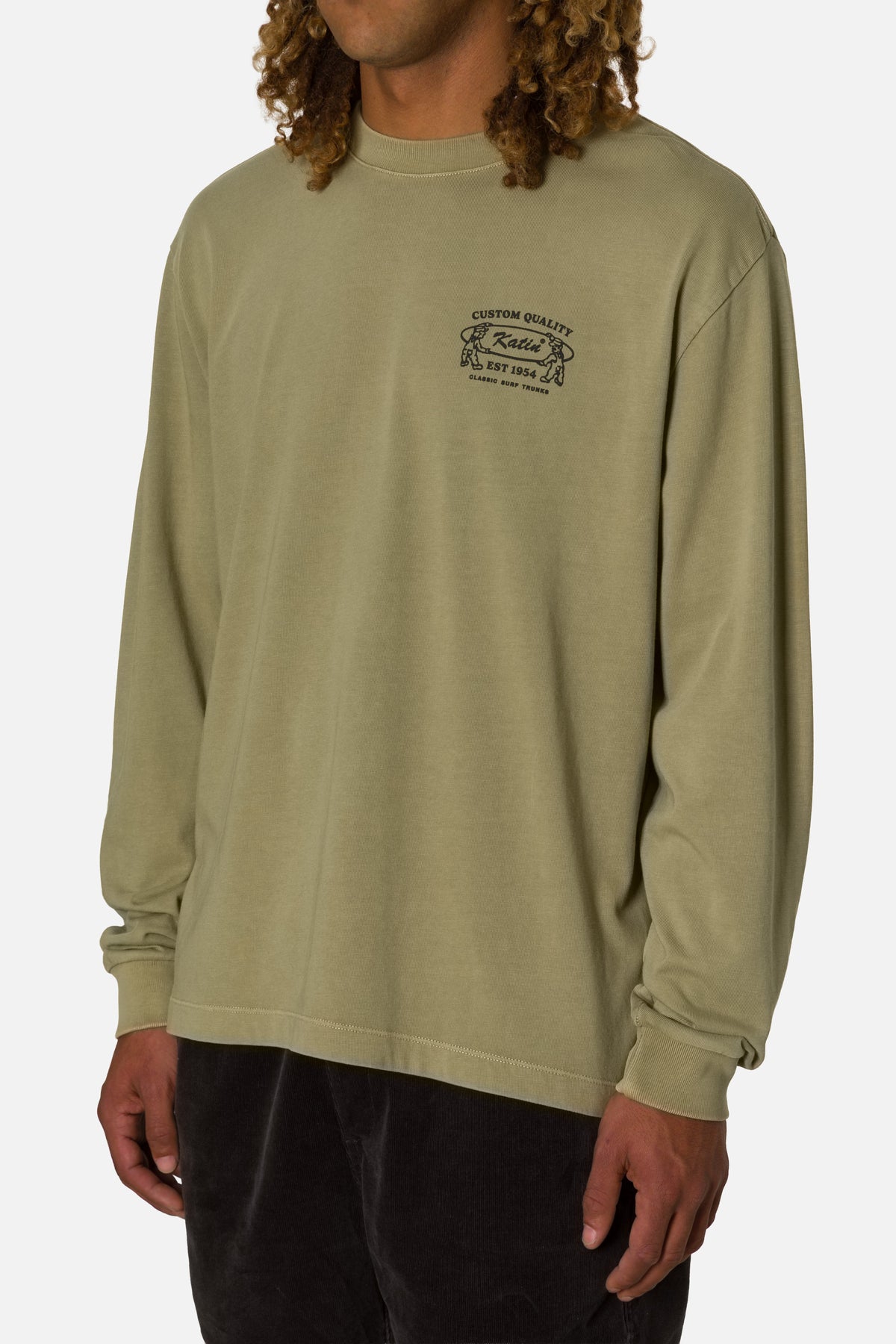 Person wearing a green long-sleeve shirt with a logo on a white background