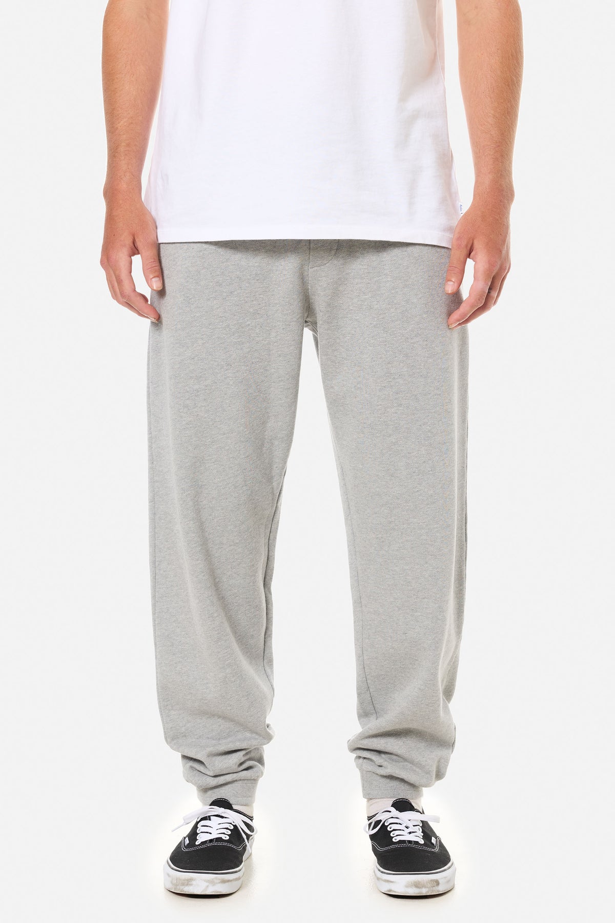 Person wearing light grey lounge pants on a white background