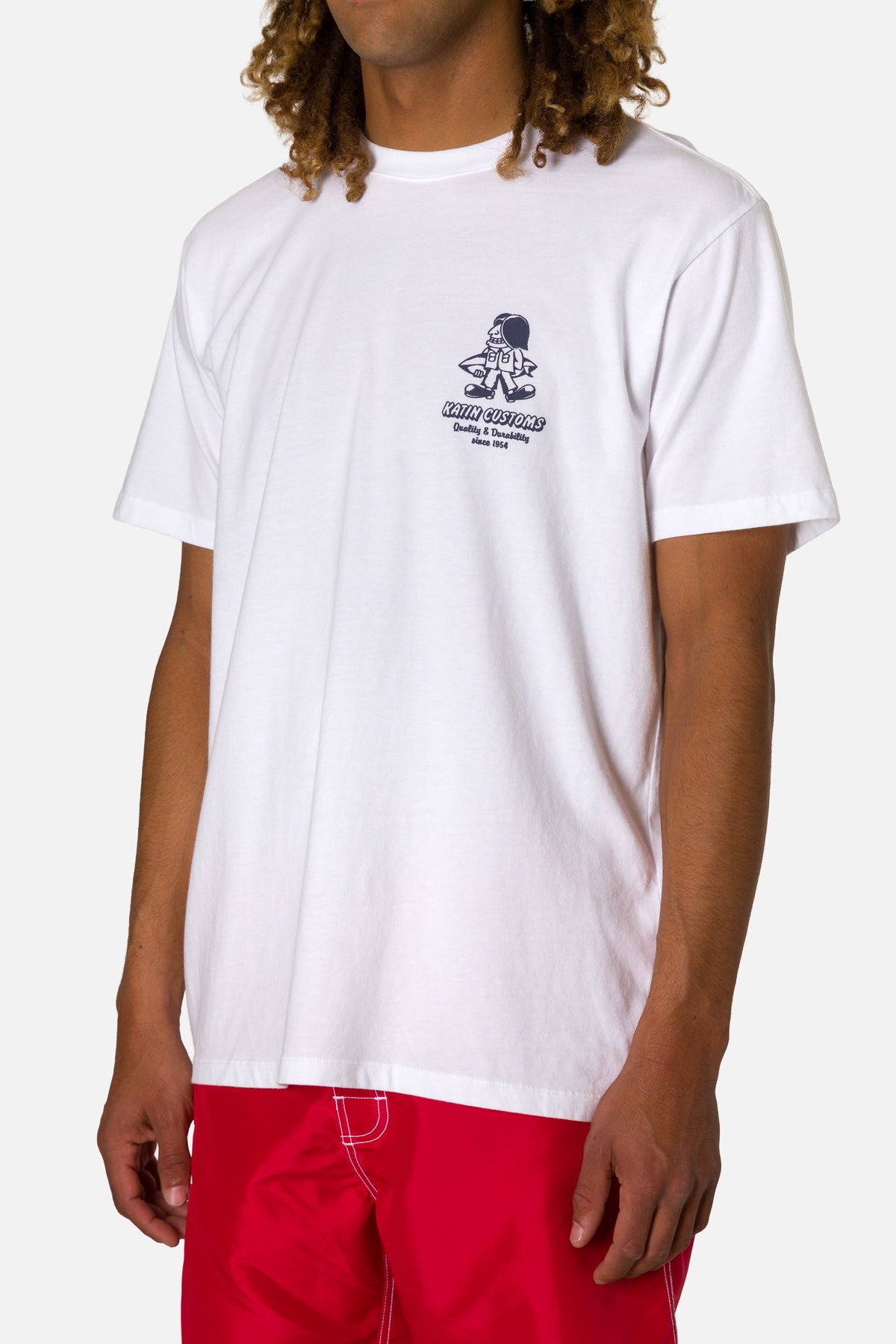 Person wearing a white t-shirt with a logo and red pants on a white background