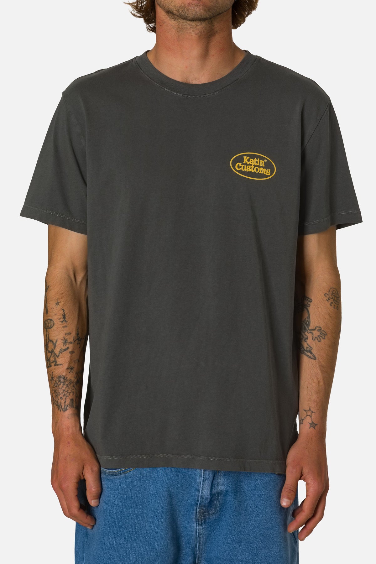 Person wearing a dark gray t-shirt with a logo on a white background