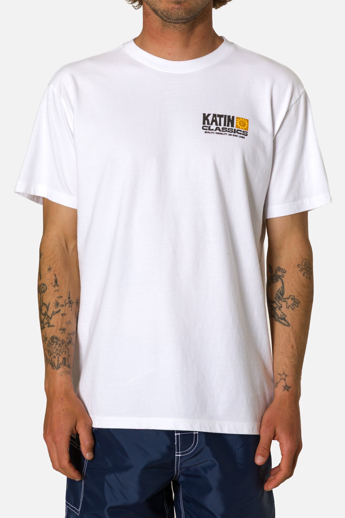 Person wearing a white t-shirt with a logo on a plain background