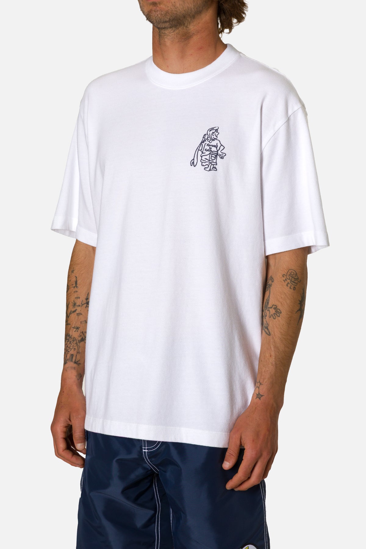 Person wearing a white t-shirt with a small graphic on a plain background