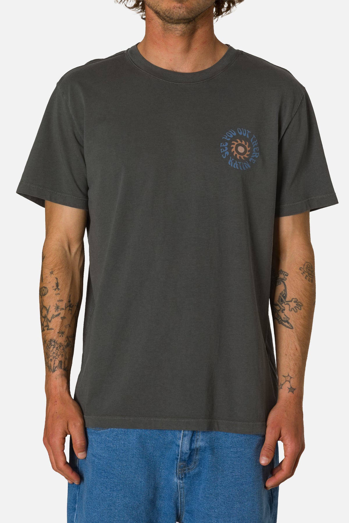 Person wearing a dark gray t-shirt with a logo on a white background