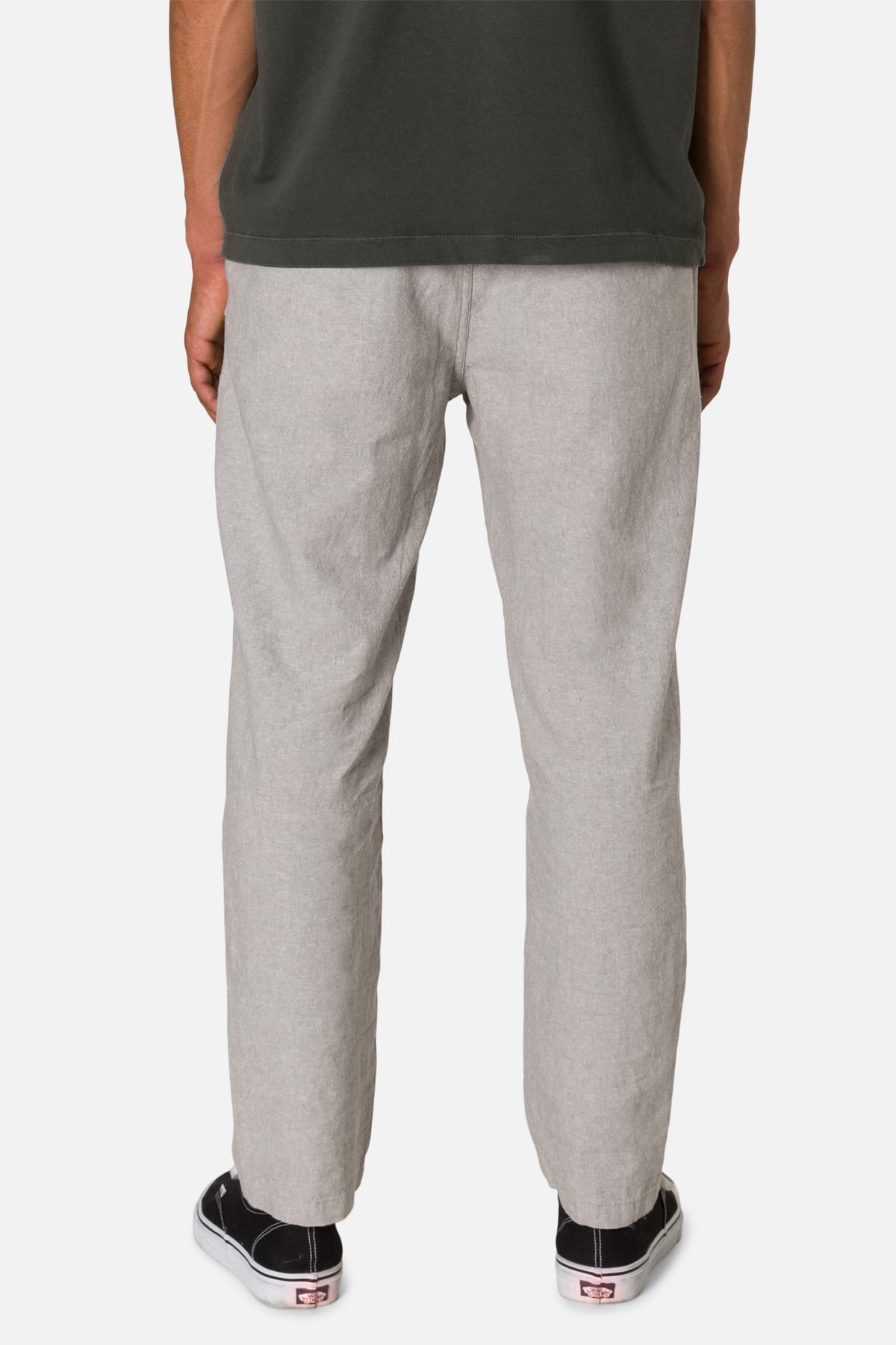 Person wearing gray pants and black sneakers on a white background