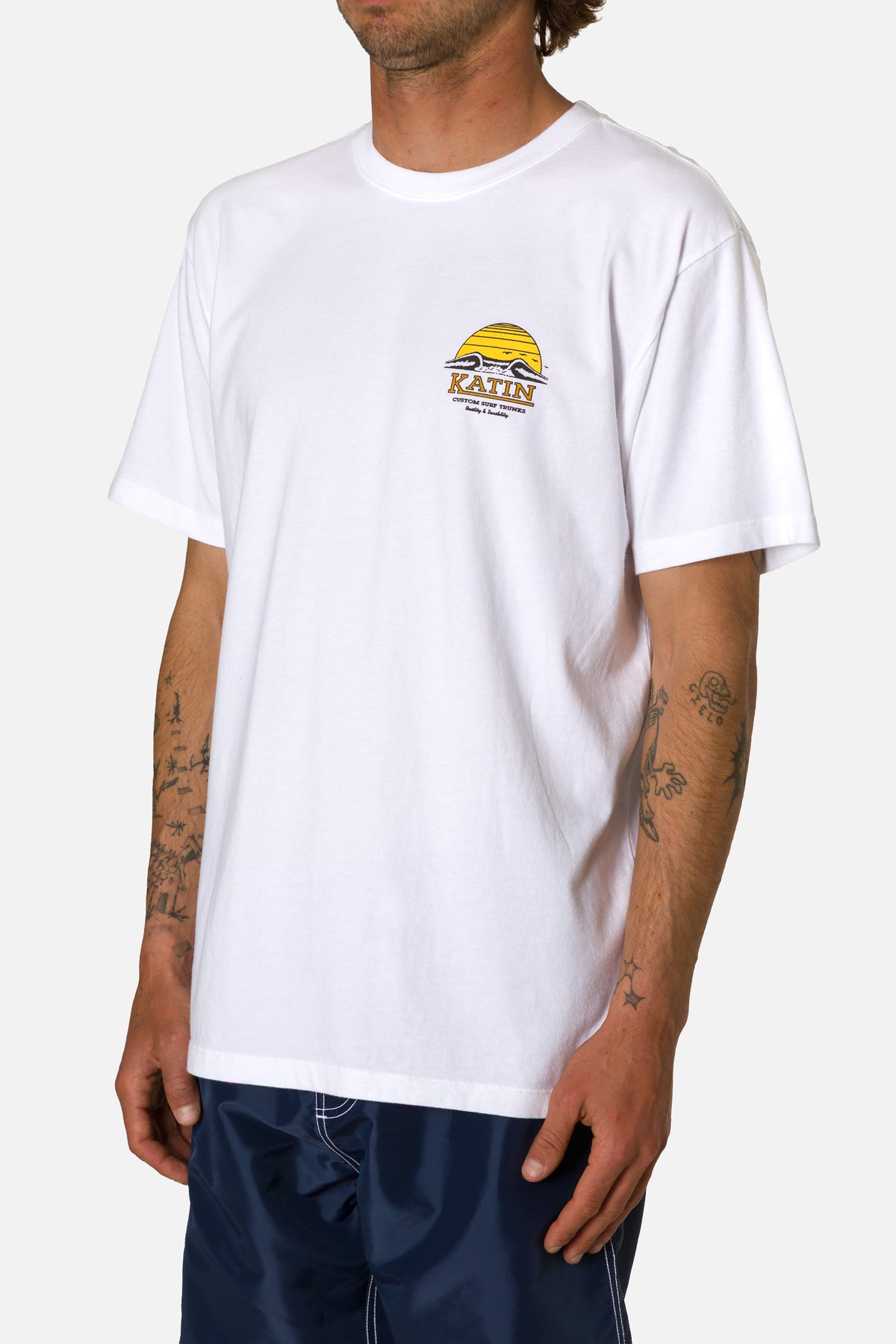 Person wearing a white t-shirt with a logo on a plain background