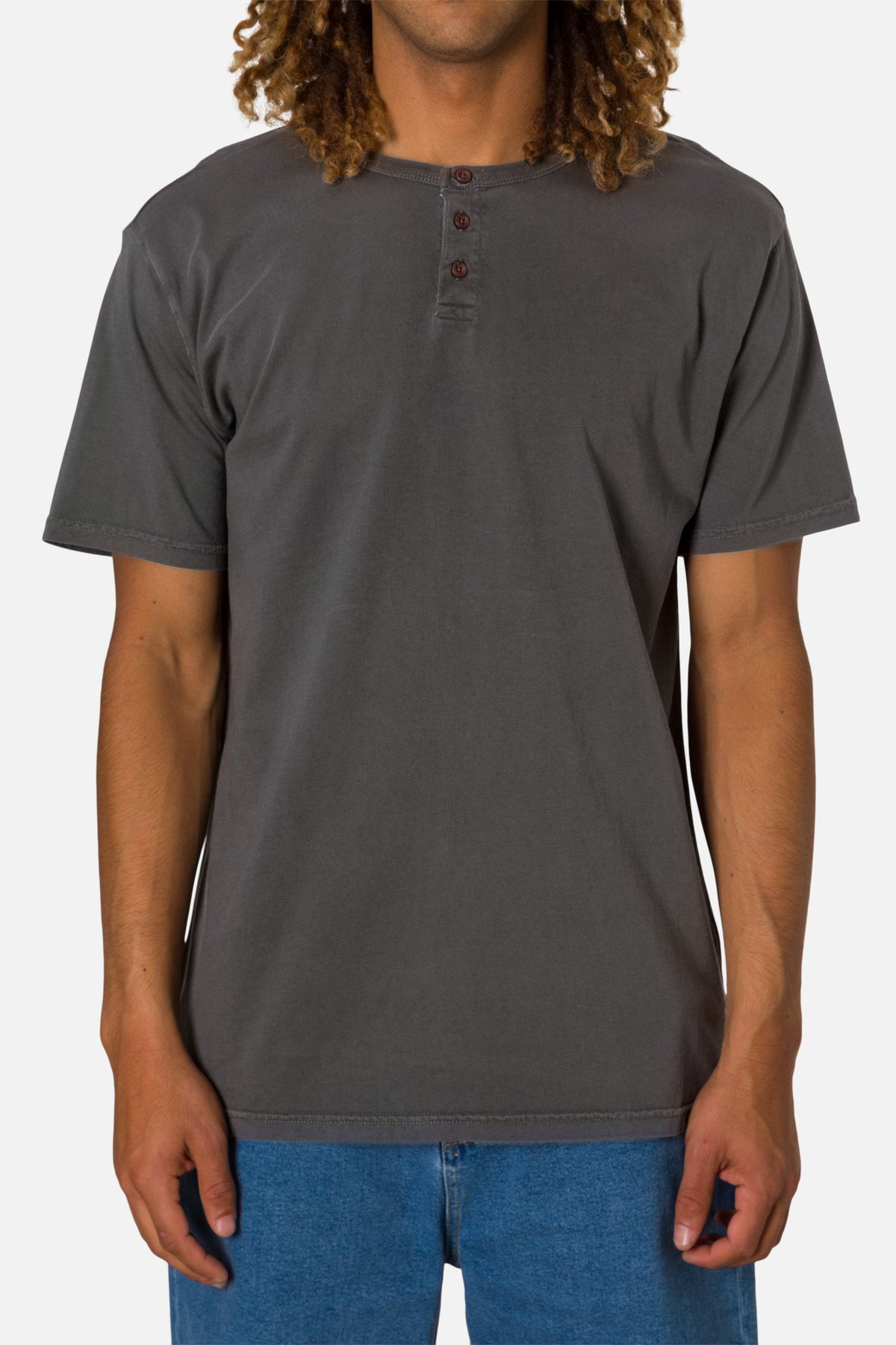 Person wearing a black wash henley shirt and blue jeans on a white background