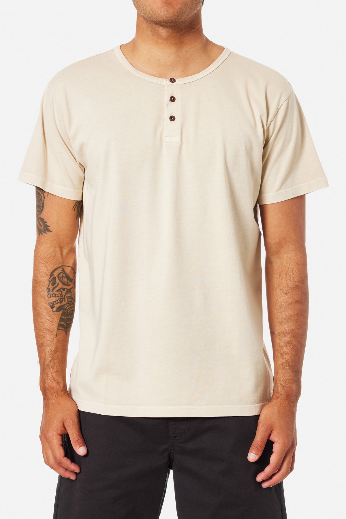 A person wearing a off white Henley shirt and blue jeans on a white background 