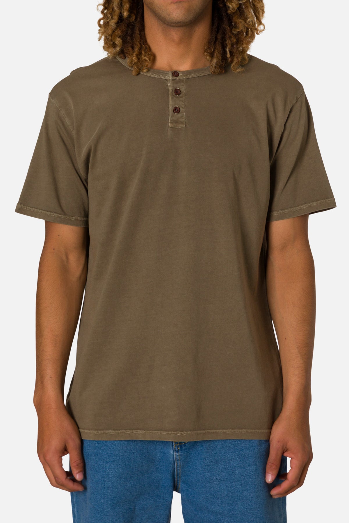 Man wearing a brown henley shirt and blue jeans on a white background