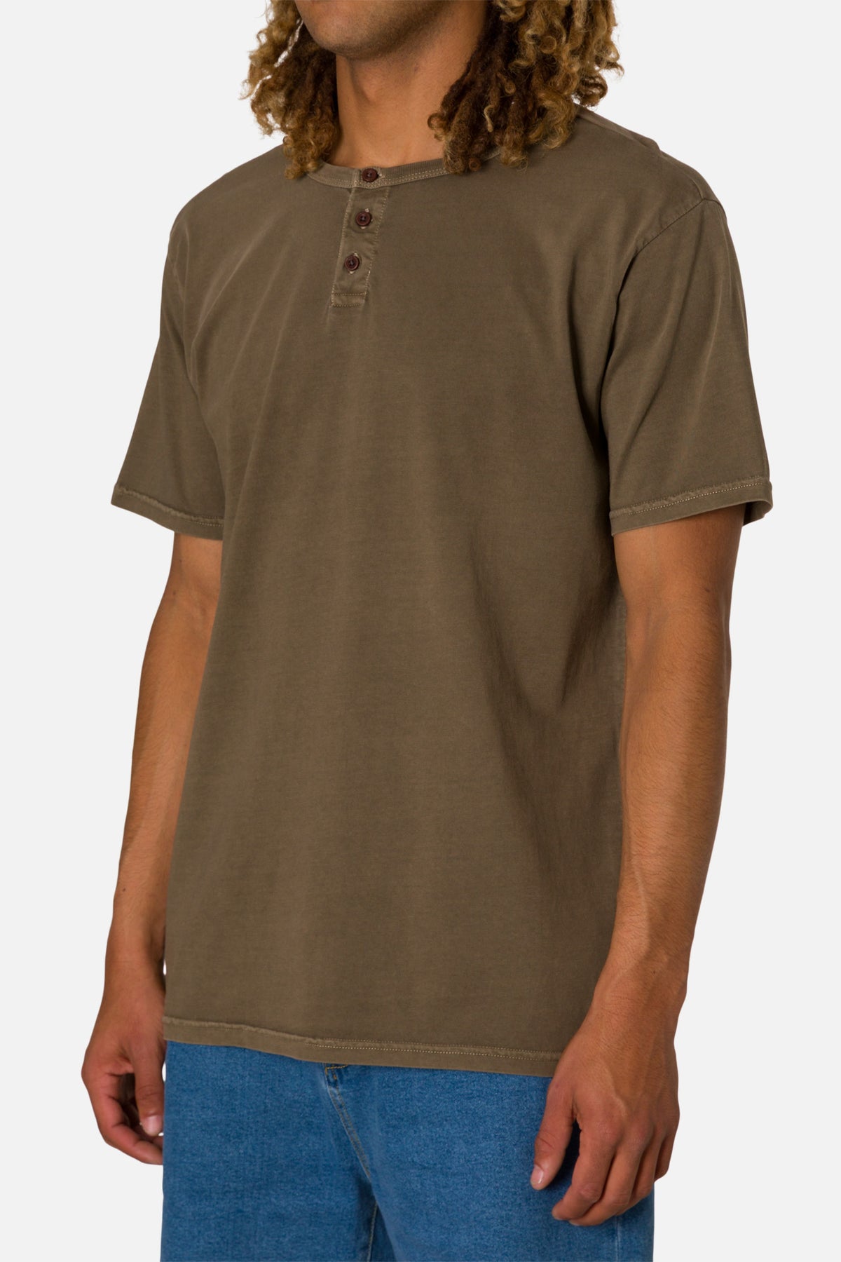 Person wearing a brown henley shirt and blue jeans on a white background