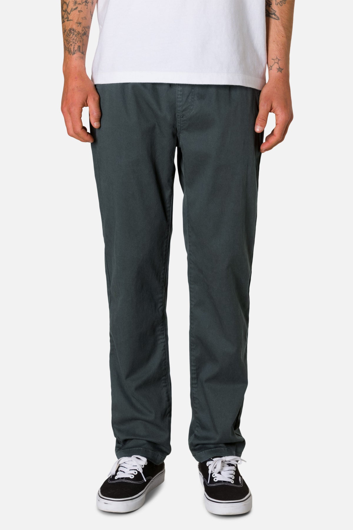 Person wearing dark gray pants and black sneakers on a white background
