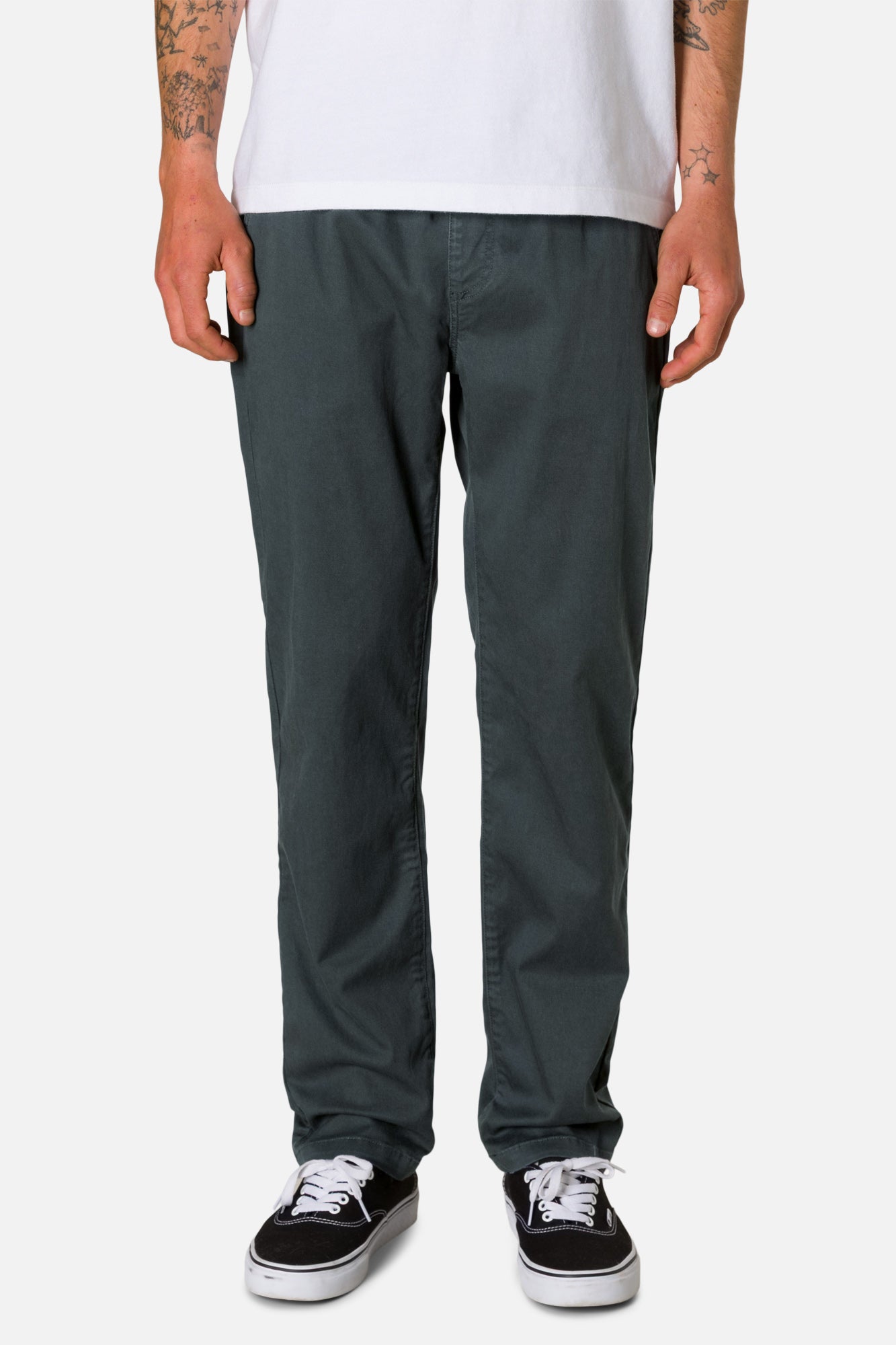 Person wearing dark gray pants and black sneakers on a white background