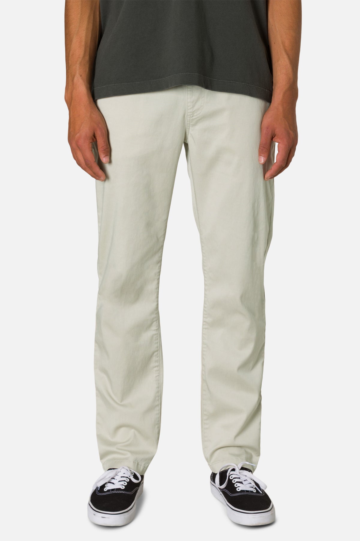 Person wearing light-colored pants and black sneakers on a white background