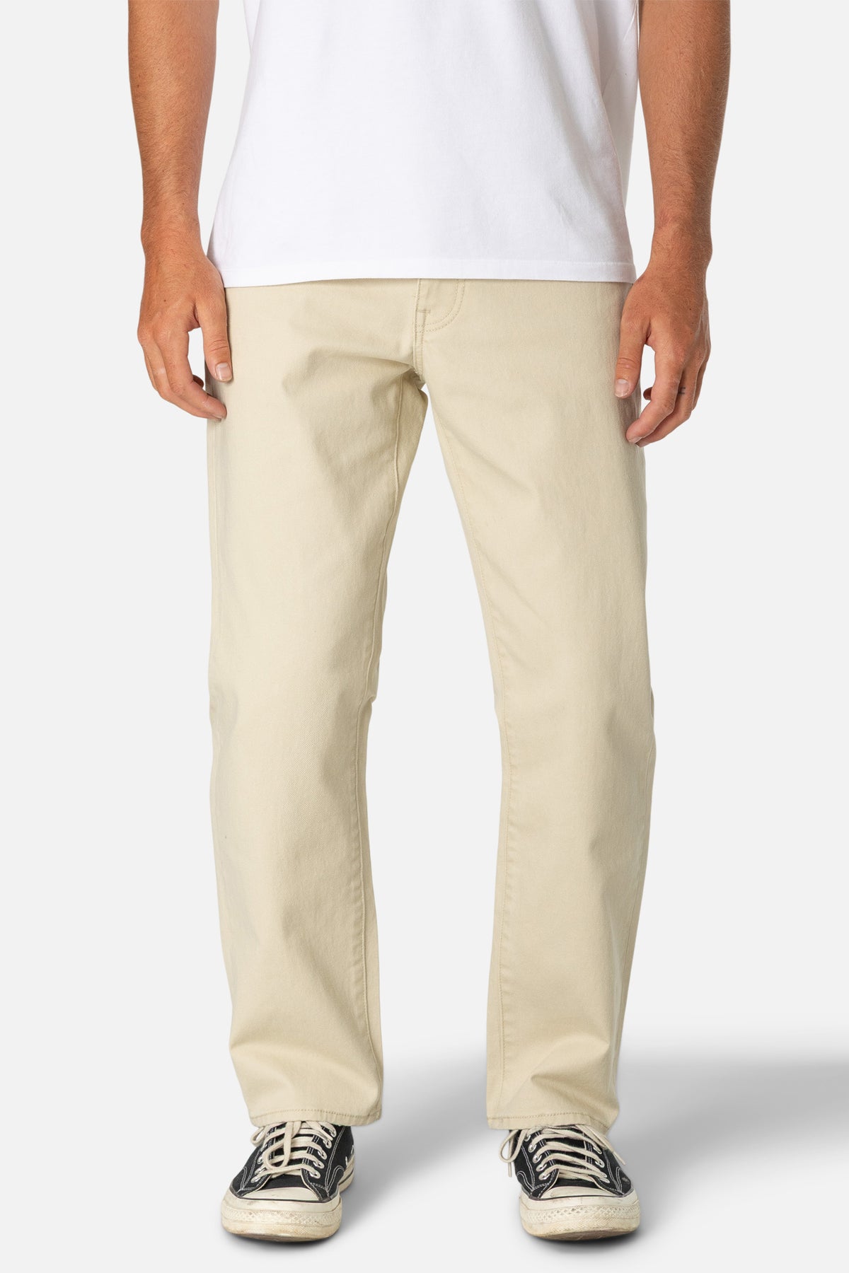 Person wearing beige pants and a white shirt on a plain background