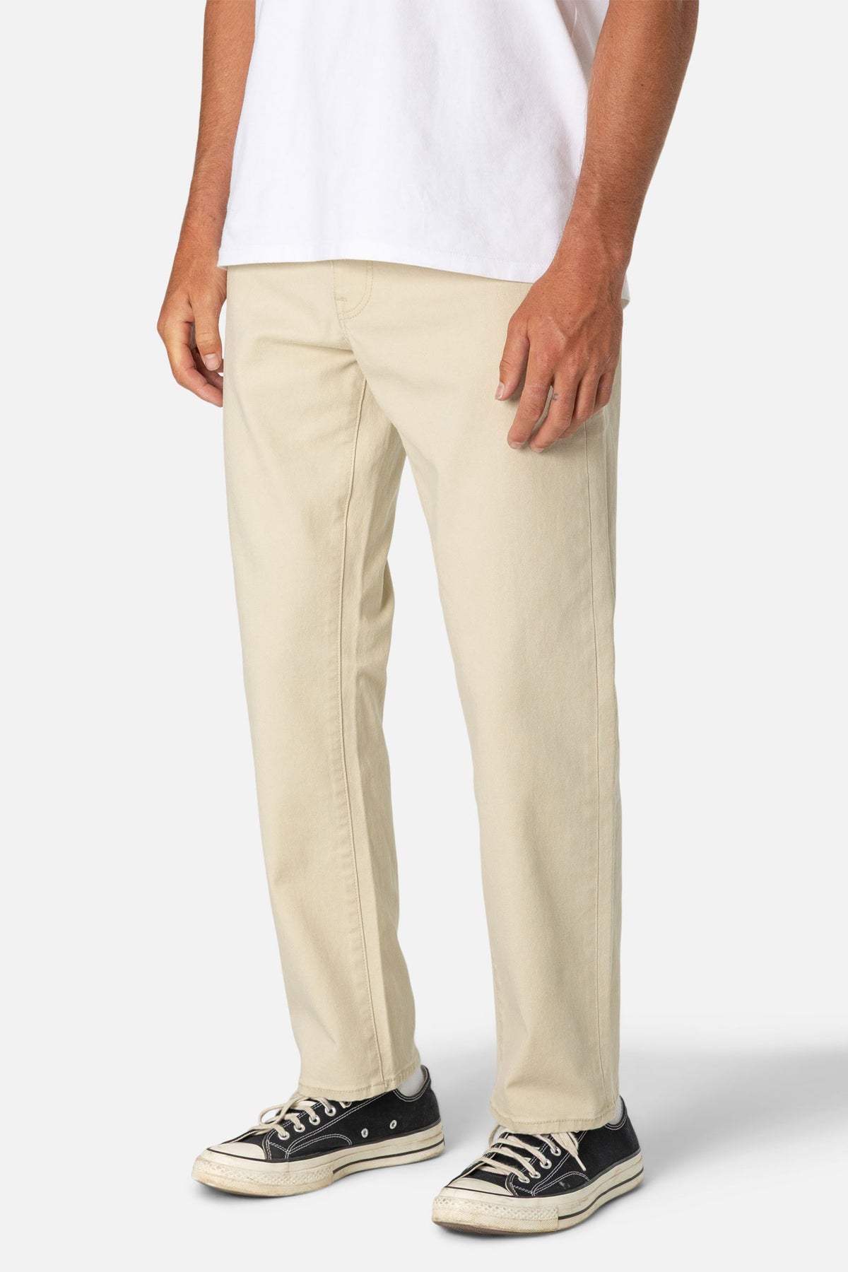 Person wearing beige pants and black sneakers on a white background