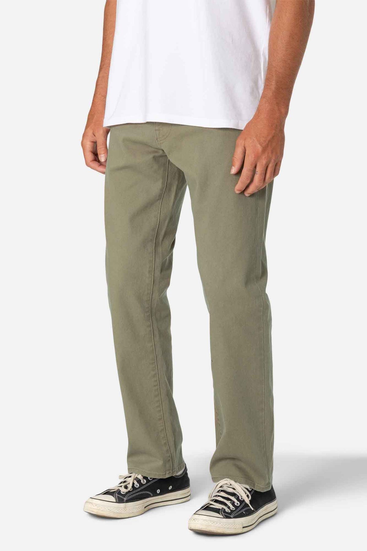 Person wearing olive green pants and black sneakers on a white background