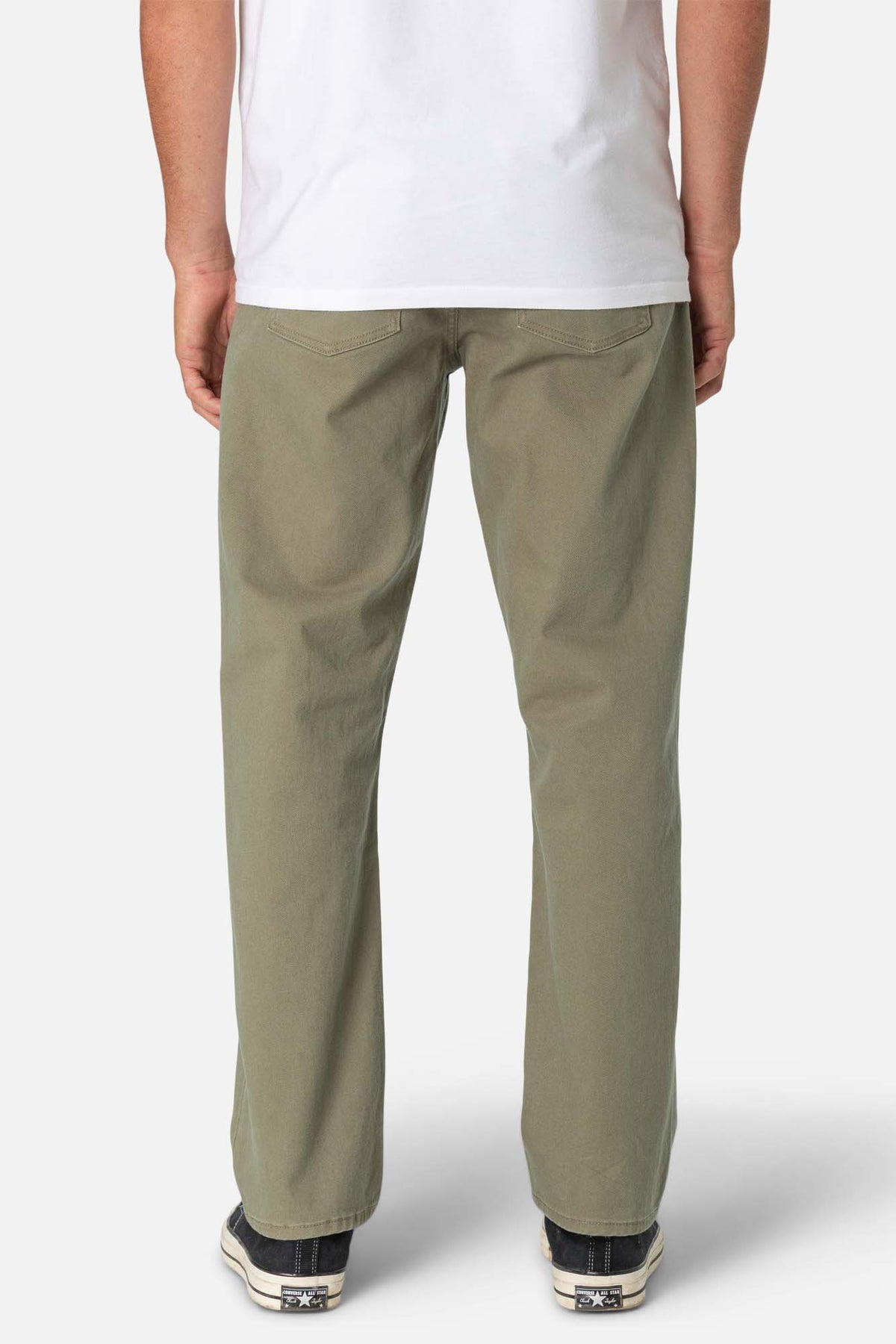 Person wearing beige pants and a white shirt on a plain background