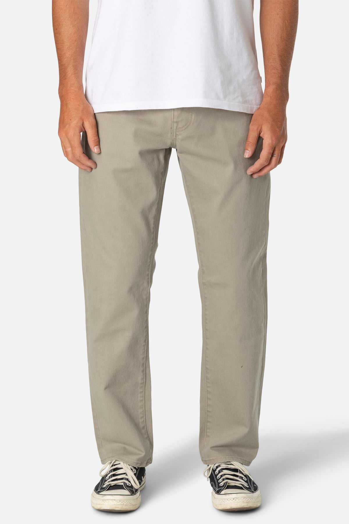 Person wearing beige pants and a white shirt on a plain background