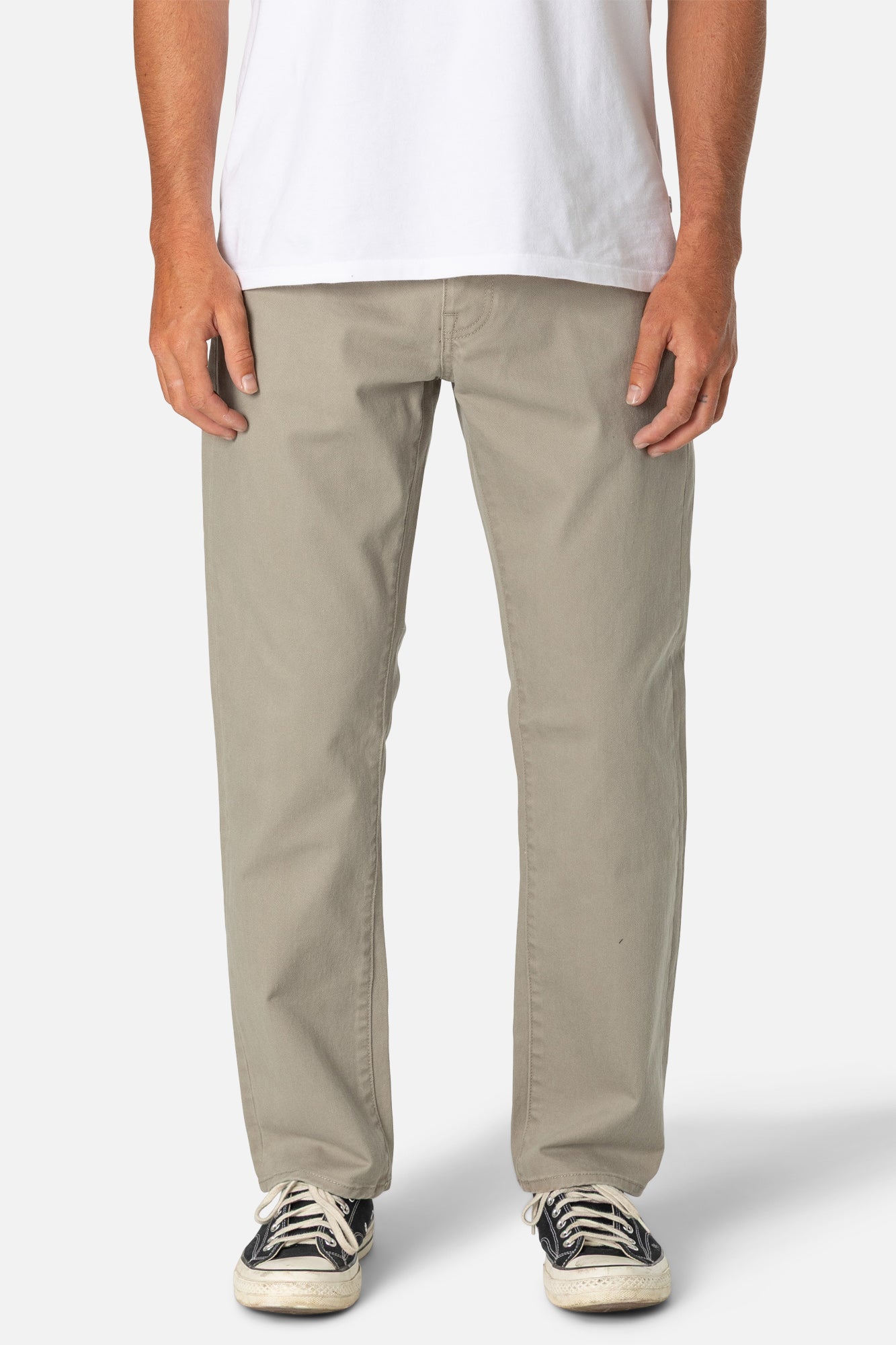 Person wearing beige pants and a white shirt on a plain background