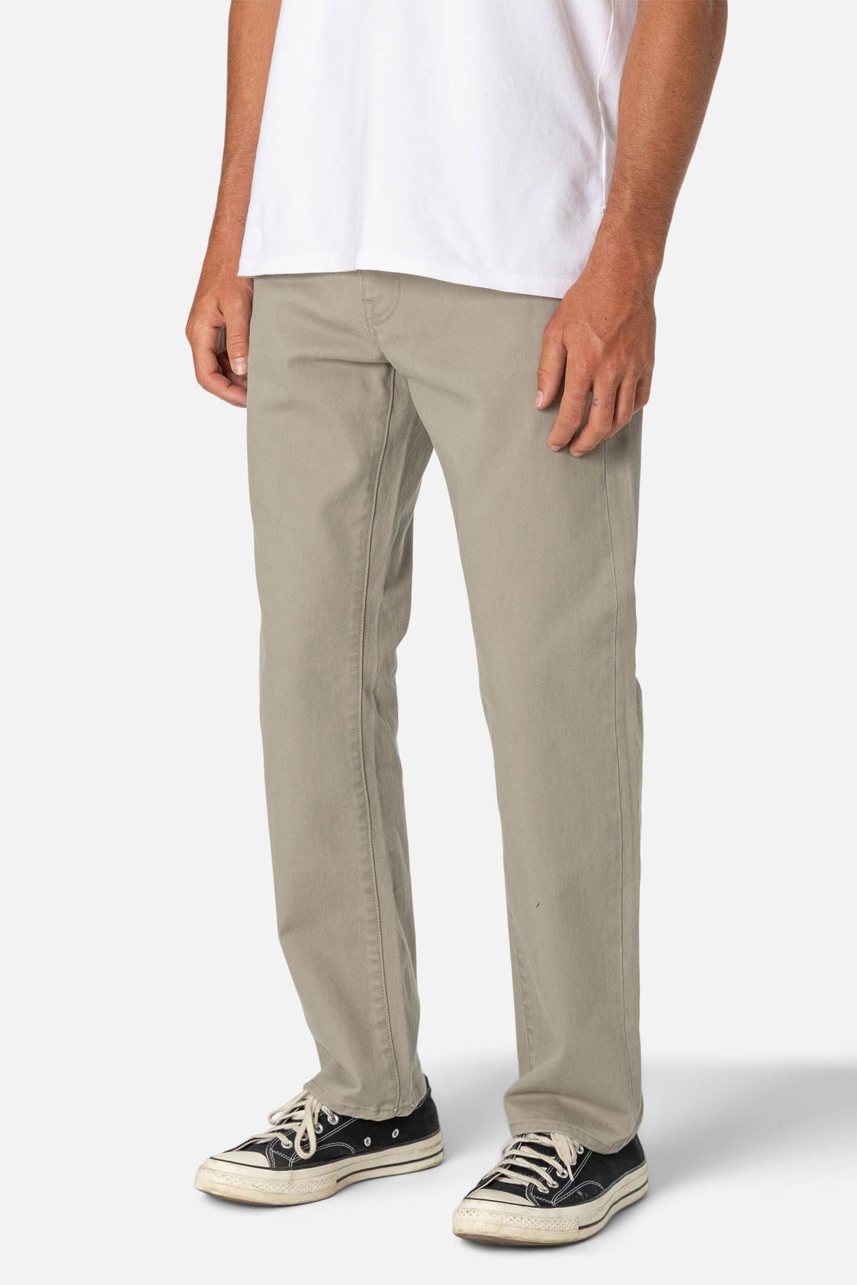 Person wearing beige pants and black sneakers on a white background