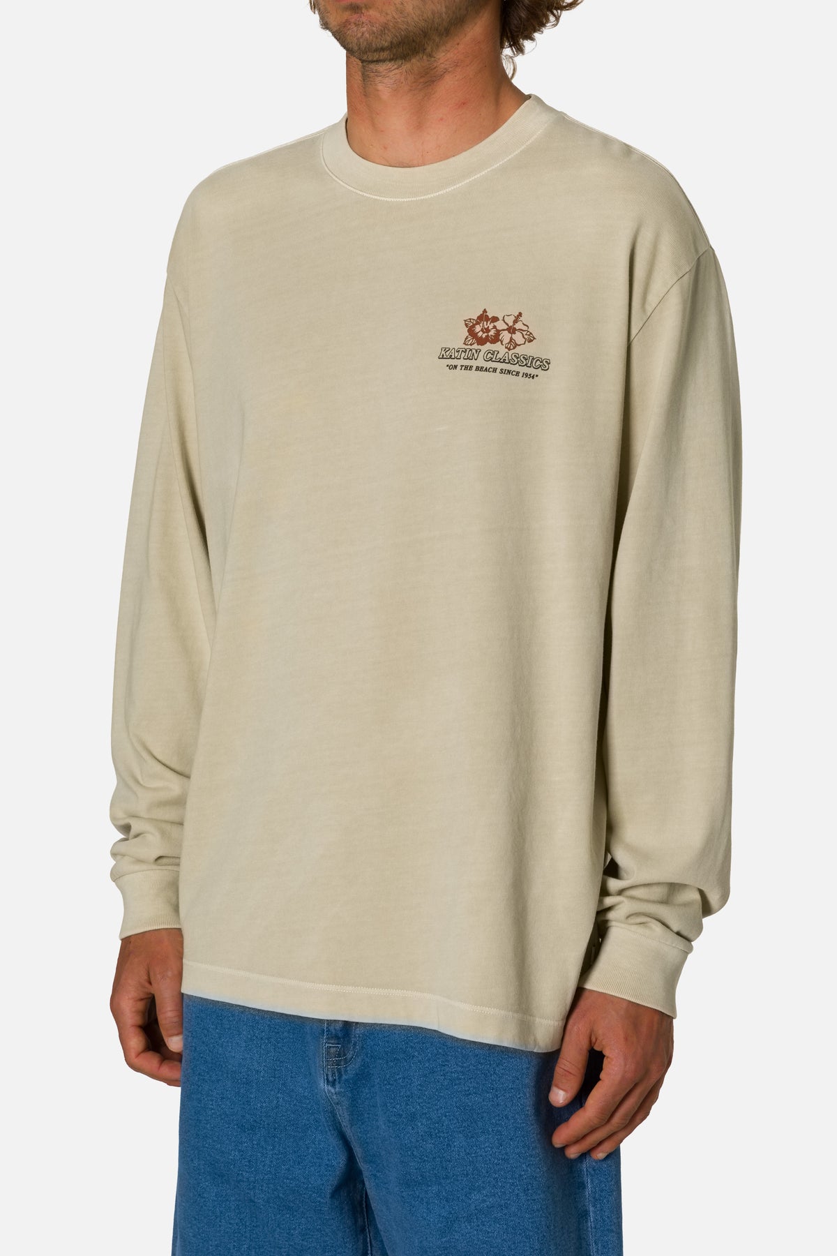 Man wearing a beige long-sleeve shirt with a logo on a white background