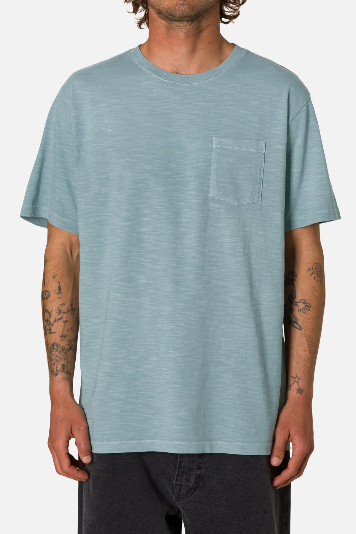 Man wearing a light blue t-shirt with a pocket on a white background