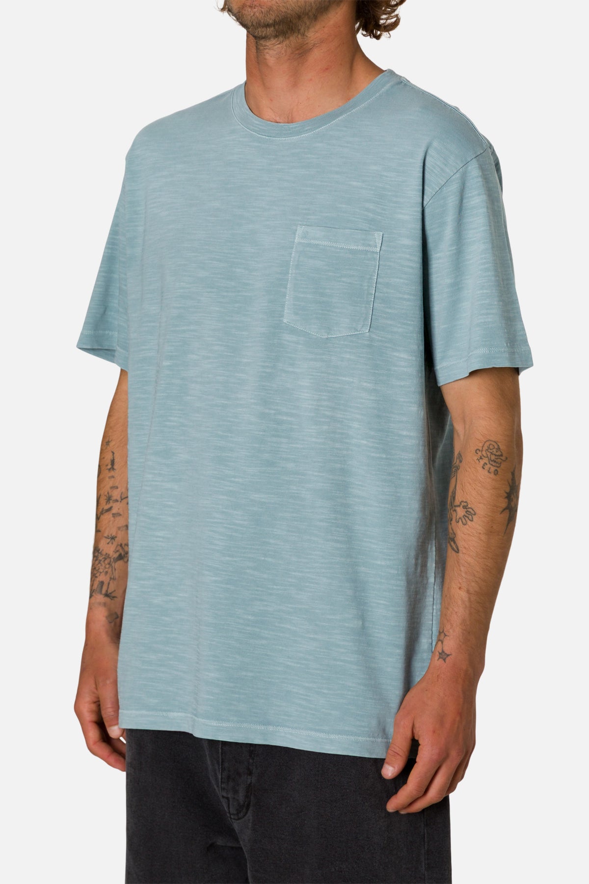 Man wearing a light blue t-shirt with a pocket on a white background