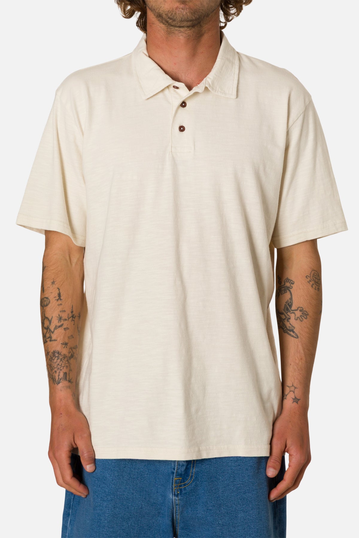Person wearing a beige polo shirt and blue jeans on a white background