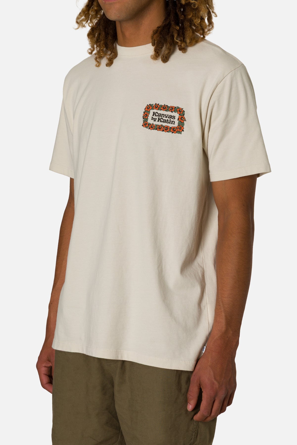 Person wearing a beige t-shirt with a logo on a white background
