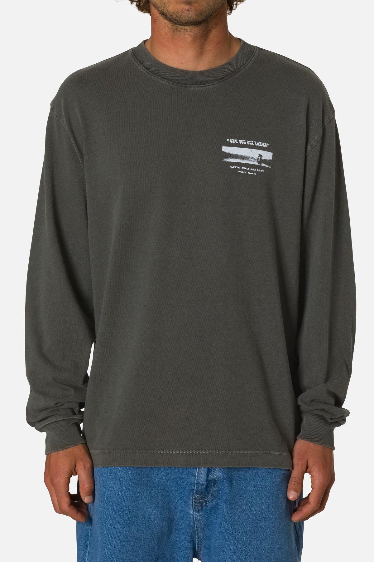 Person wearing a dark gray long-sleeve shirt with a logo on a white background