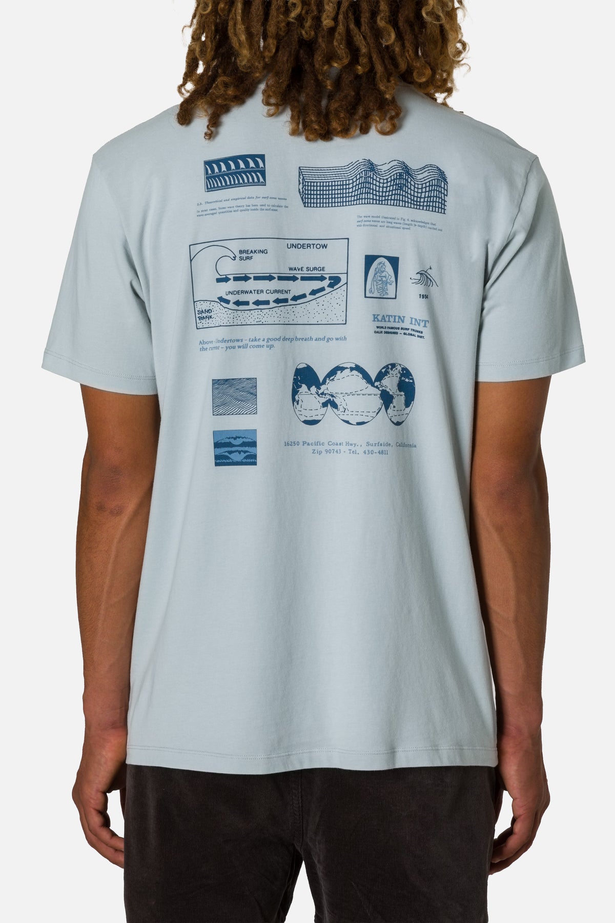 Person wearing a light gray t-shirt with blue graphics on the back, standing against a white background