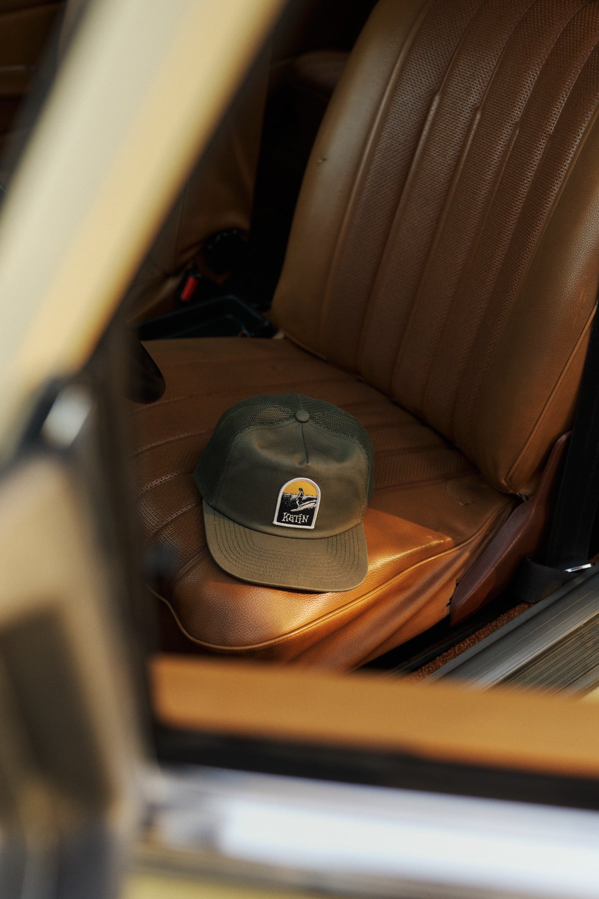 Green hat on a brown leather car seat